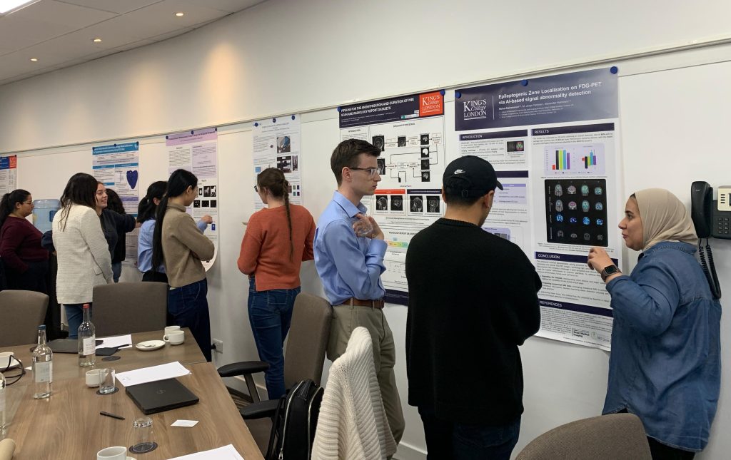 Attendees of the Medical Imaging CDT event viewing and discussing academic posters in a seminar room, with research charts and visuals displayed on the walls